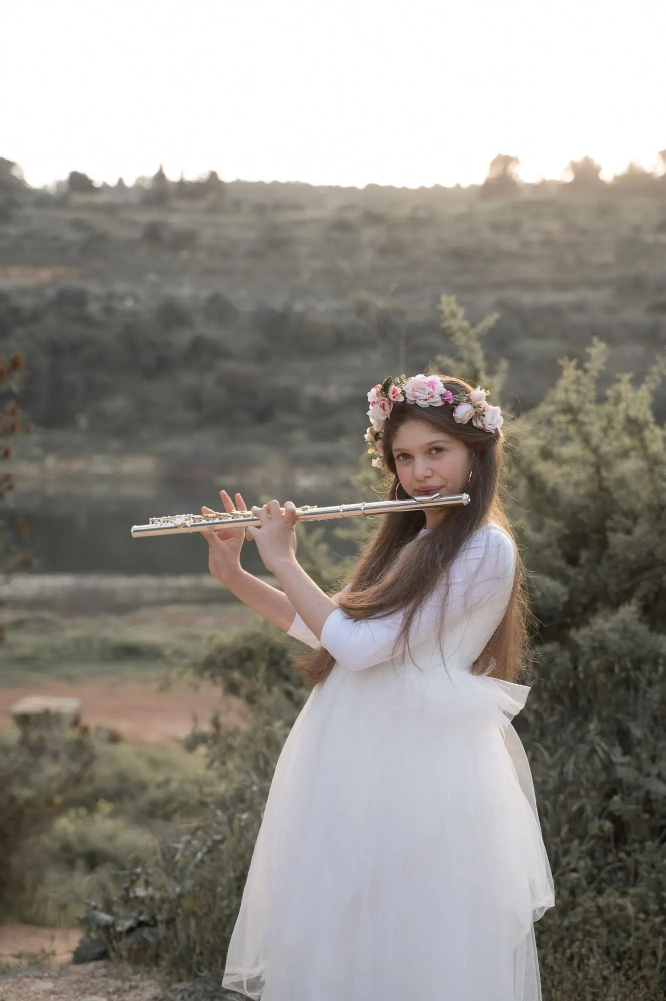 נערה עם זר פרחים מנגנת בחליל צד בטבע