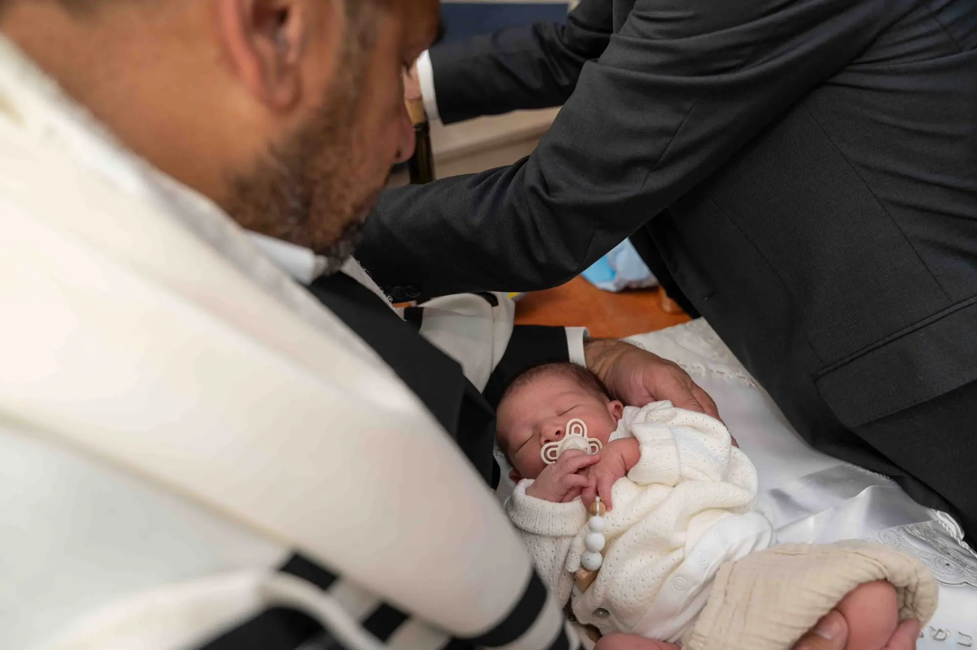 תינוק רך בזרועות אביו בברית מילה