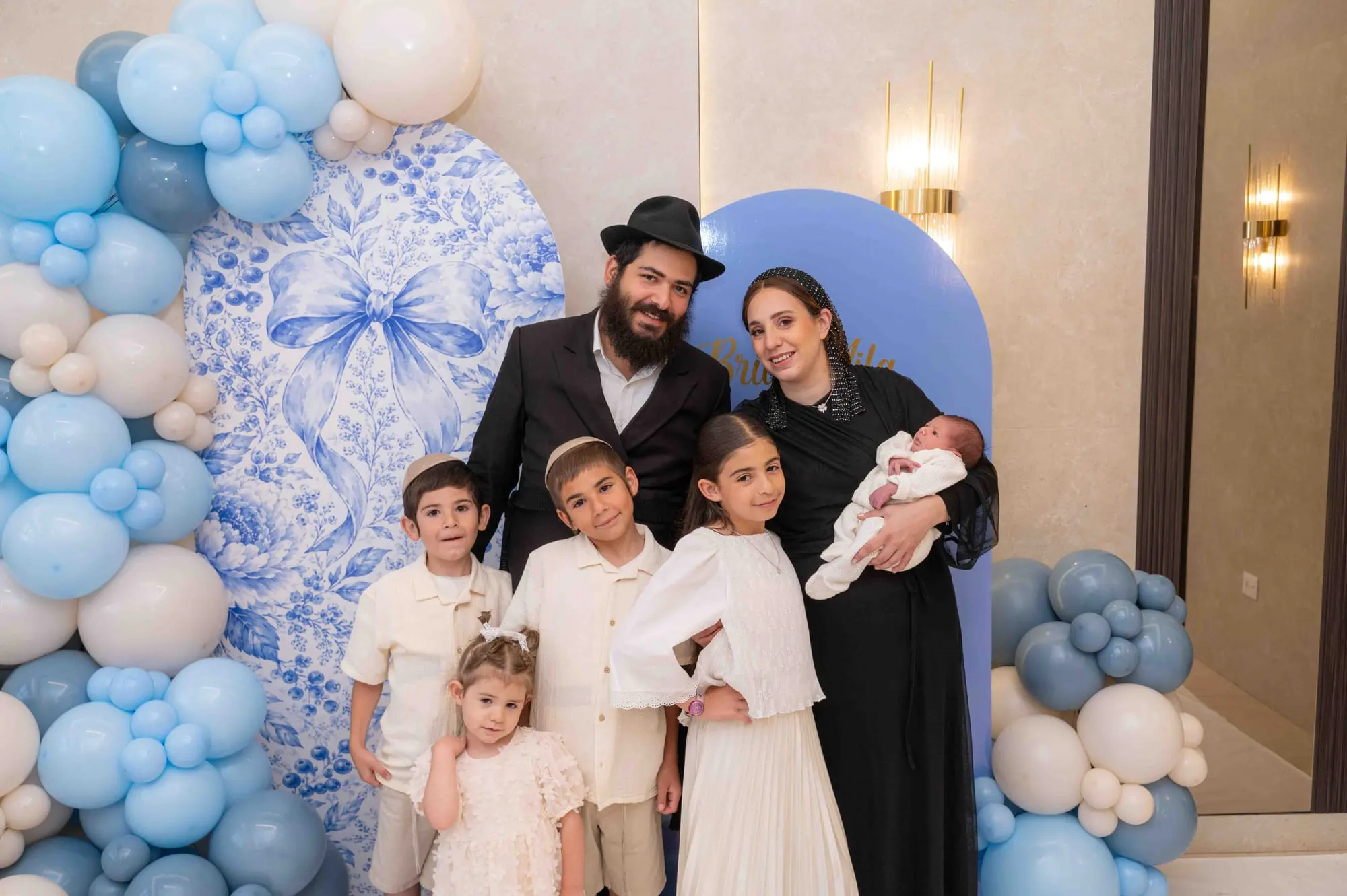משפחה מצטלמת עם התינוק על רקע עיצוב בלונים