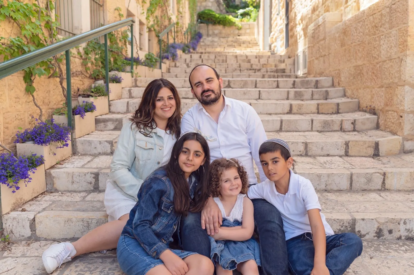 משפחה יושבת על מדרגות אבן ירושלמיות