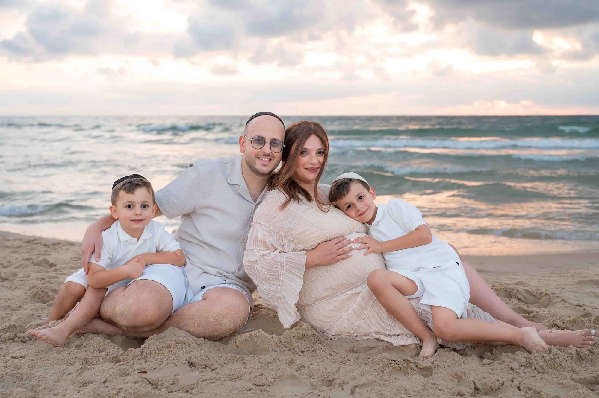 משפחה על החוף סביב אמא בהיריון