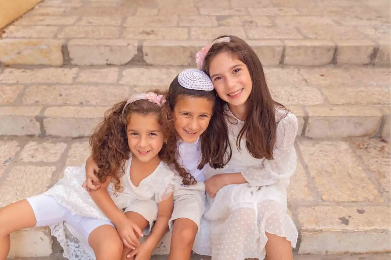 שלוש אחיות בשמלות לבנות על מדרגות אבן