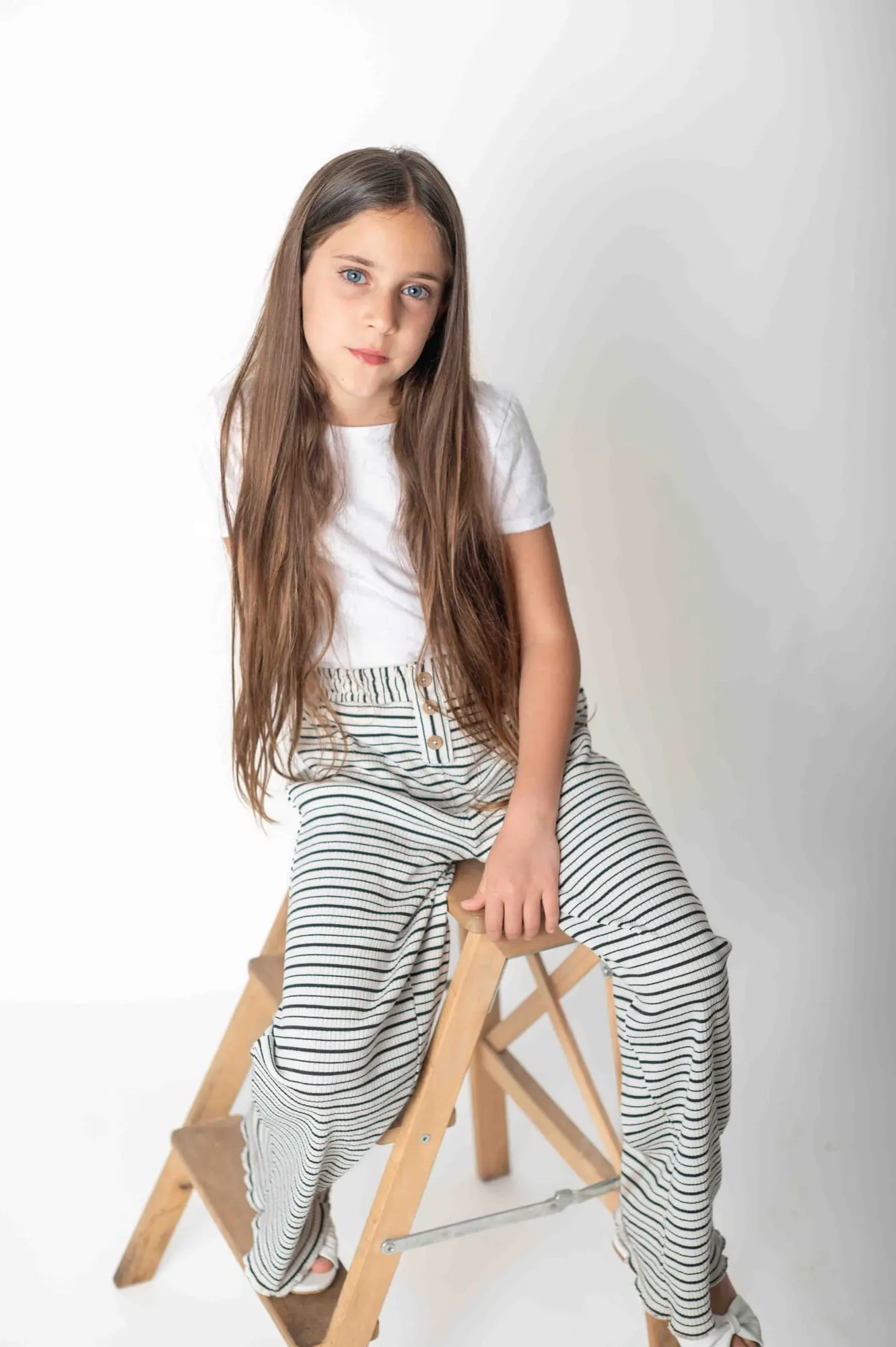ילדה יושבת על שרפרף בסטודיו